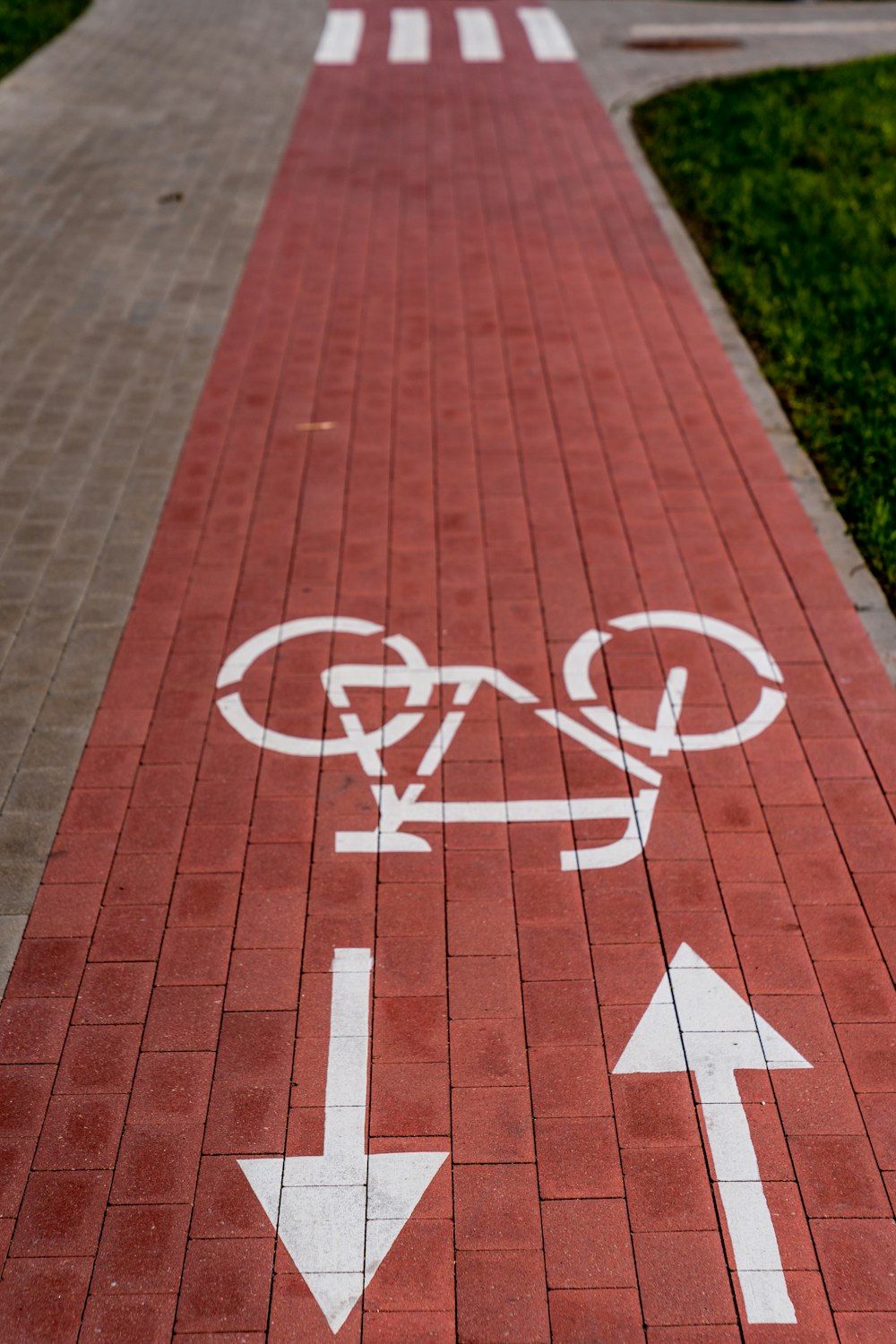 a red brick sidewalk with white arrows and a bicycle lane