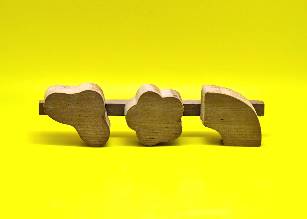 three wooden elephants on a yellow background