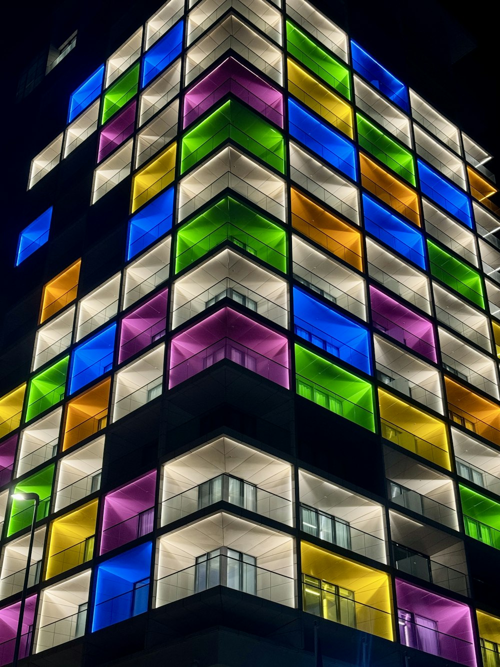 a multicolored building is lit up at night