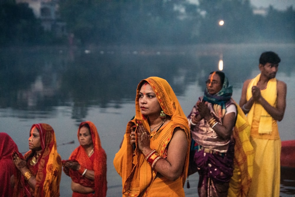 a group of women standing in front of a body of water