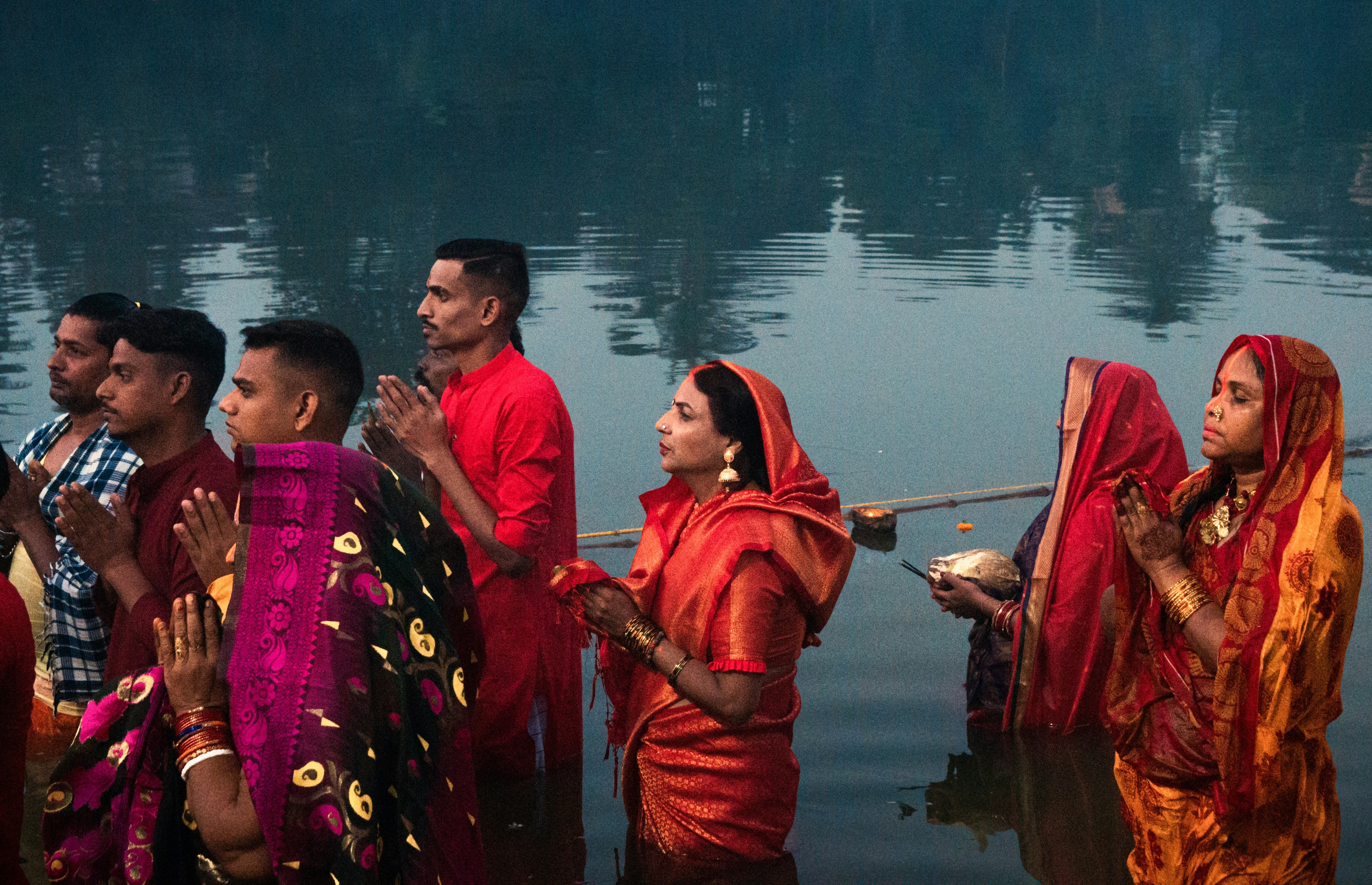 A group of people performing a traditional 'Ganga Aarti' at a clean ghat, with the river water looking clear and serene in the foreground, symbolizing hope and devotion.