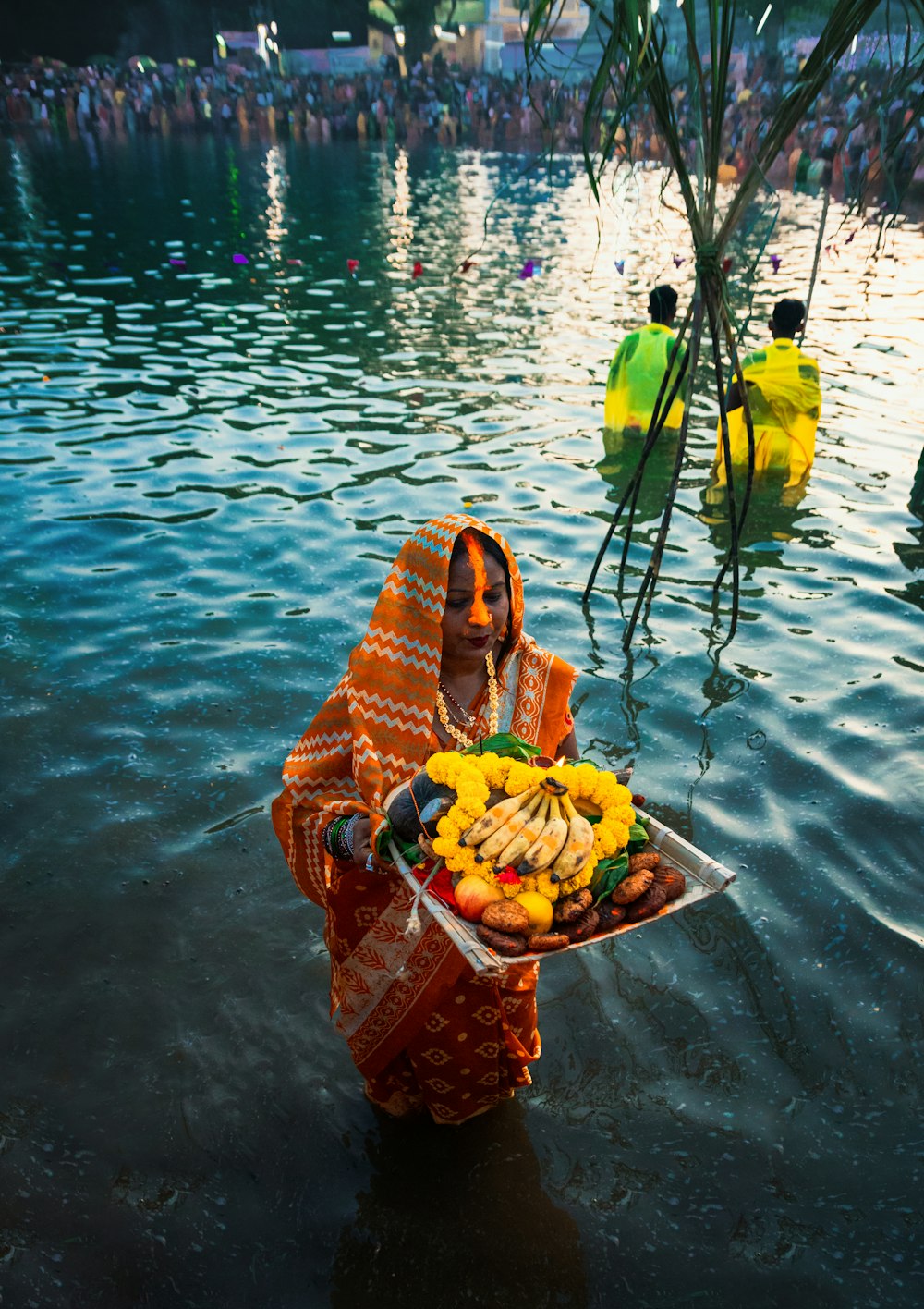 a woman standing in a body of water holding a basket of fruit
