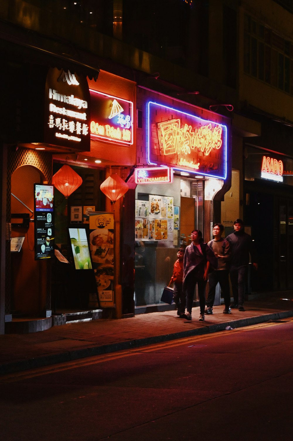 a group of people walking down a street at night