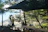 Couple enjoying breakfast on a wooden deck overlooking misty pine-covered mountains in the morning light.