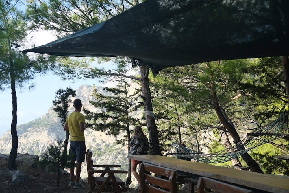 a man standing next to a wooden bench under an umbrella