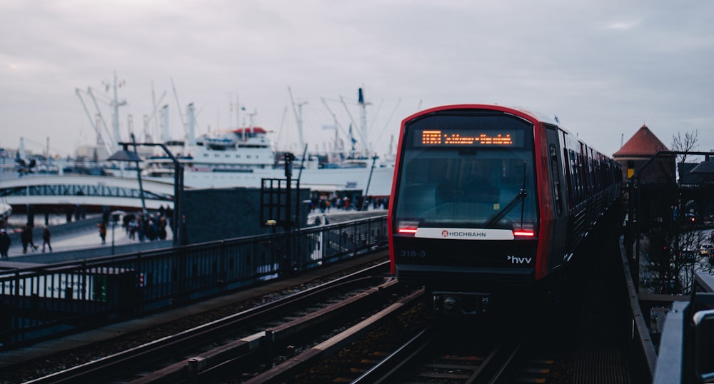 a red train traveling down train tracks next to a harbor