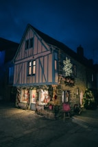 A cozy outdoor building facade decorated with glowing LED snowflakes and shooting stars at night