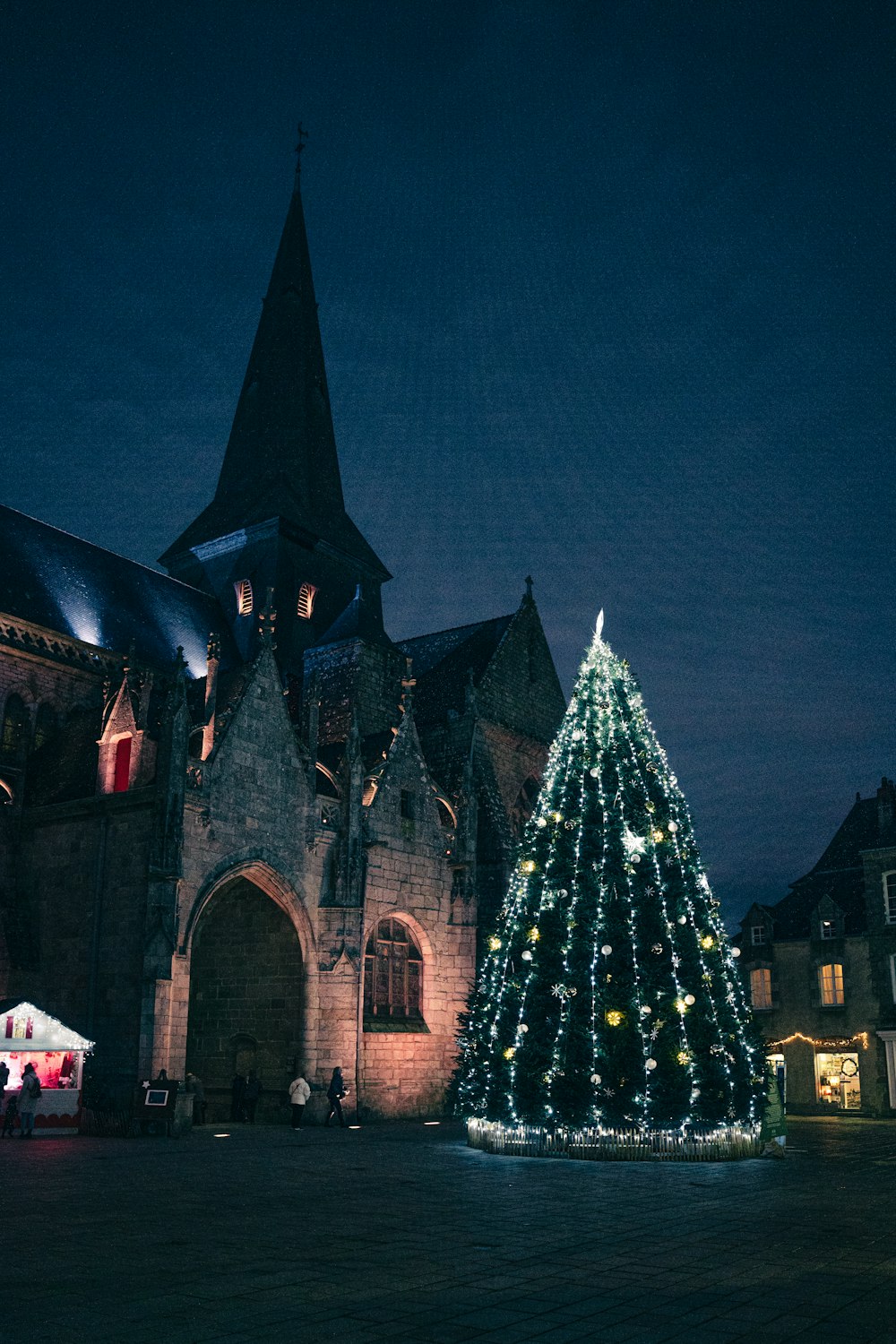 a lit christmas tree in front of a church