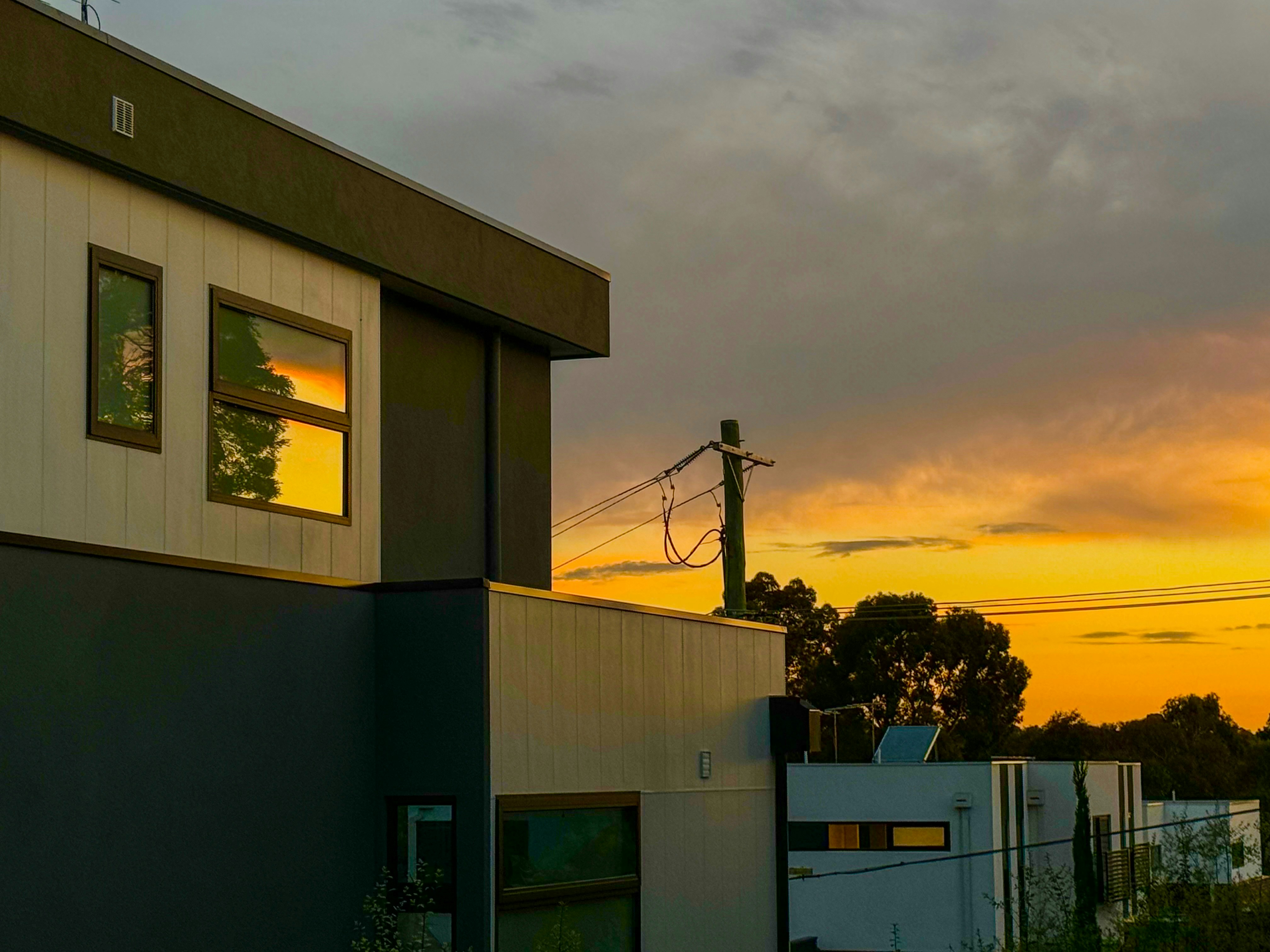 the sun is setting over a building and power lines