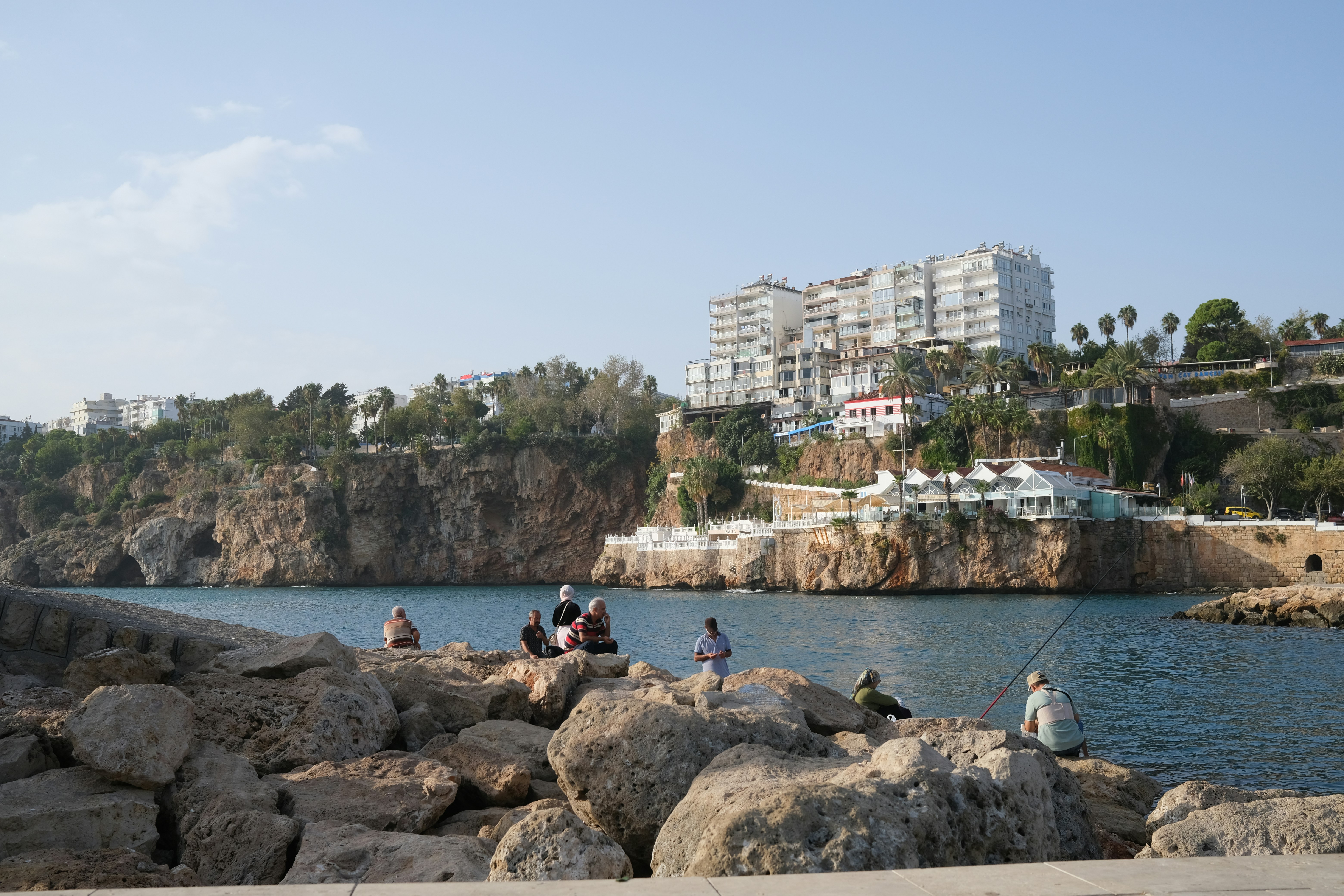 a group of people sitting on rocks next to a body of water