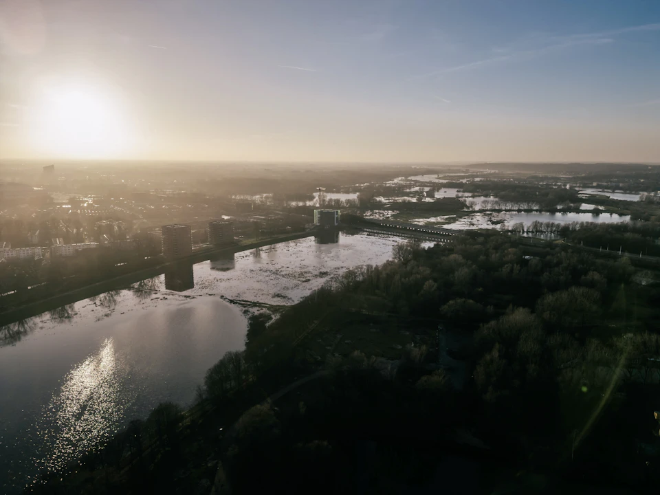 Cityscape with a serene river flowing through it under a clear blue evening sky