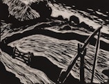 A monochromatic illustration featuring a dynamic composition with curved and sharp lines. It includes abstract forms that resemble a river or stream flowing past angular and curved structures, possibly rocks or hills, with a prominent object resembling a wooden bridge or structure.