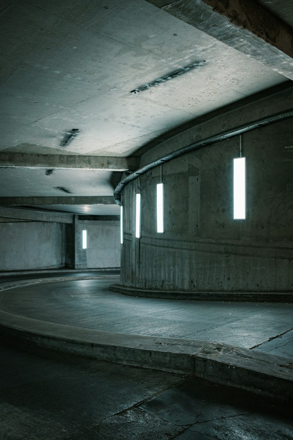 an empty parking garage with concrete floors and round windows