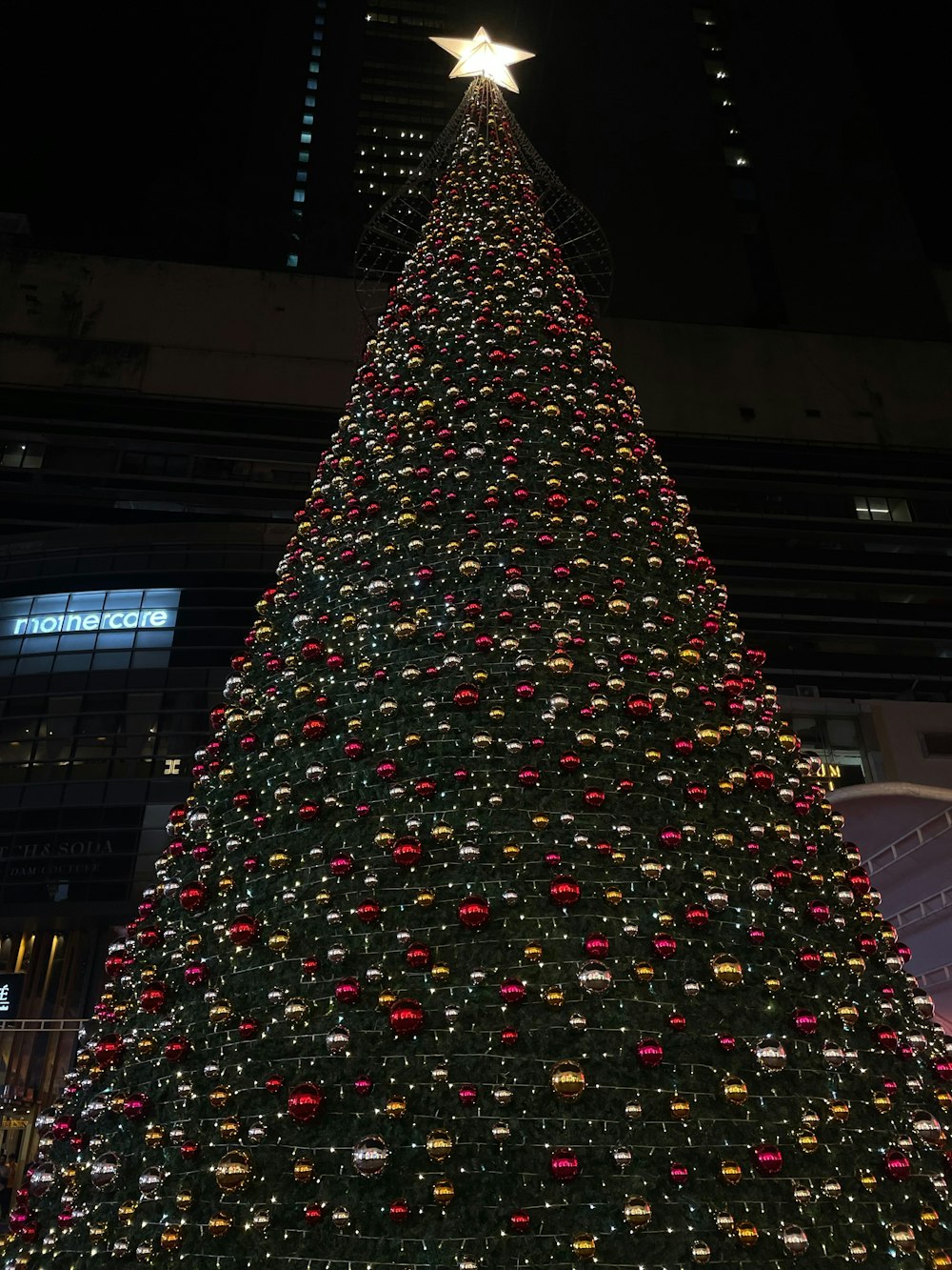 a large christmas tree is lit up at night
