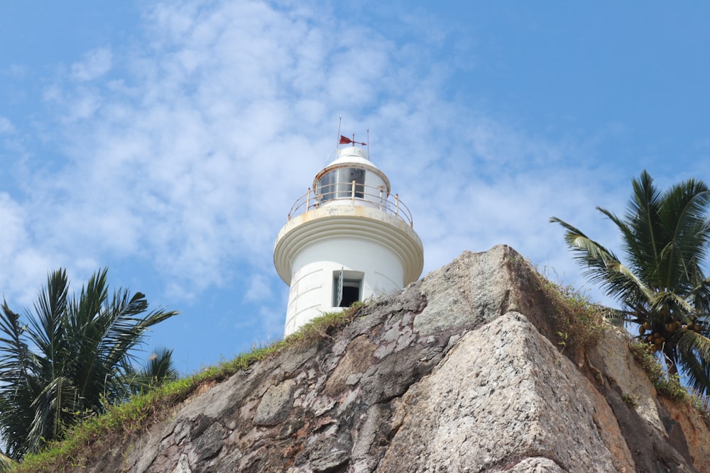 a white lighthouse on top of a rocky outcropping