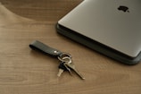 Gold key placed on a black leather portfolio next to a laptop.