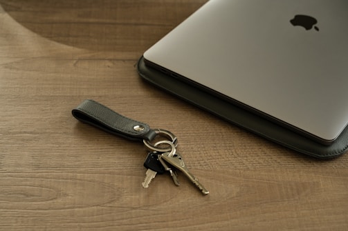Gold key placed on a black leather portfolio next to a laptop.