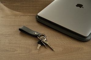 Close-up of a sleek minimalist metal keychain resting on a wooden table.
