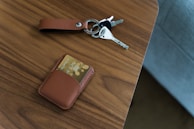 A leather keychain with a subtle embossed design, attached to a set of keys on a marble countertop.