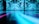 A large-scale digital art installation featuring swirling patterns of blue and cyan shades on a wall. The reflective surface in the foreground extends the patterns, creating a mesmerizing and immersive visual experience.