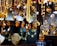 An array of amber jewelry, including necklaces and pendants, is displayed hanging in a showcase. The pieces are intricately designed with a range of warm amber tones, complemented by silver elements. Price tags are attached to each item, indicating they are for sale.