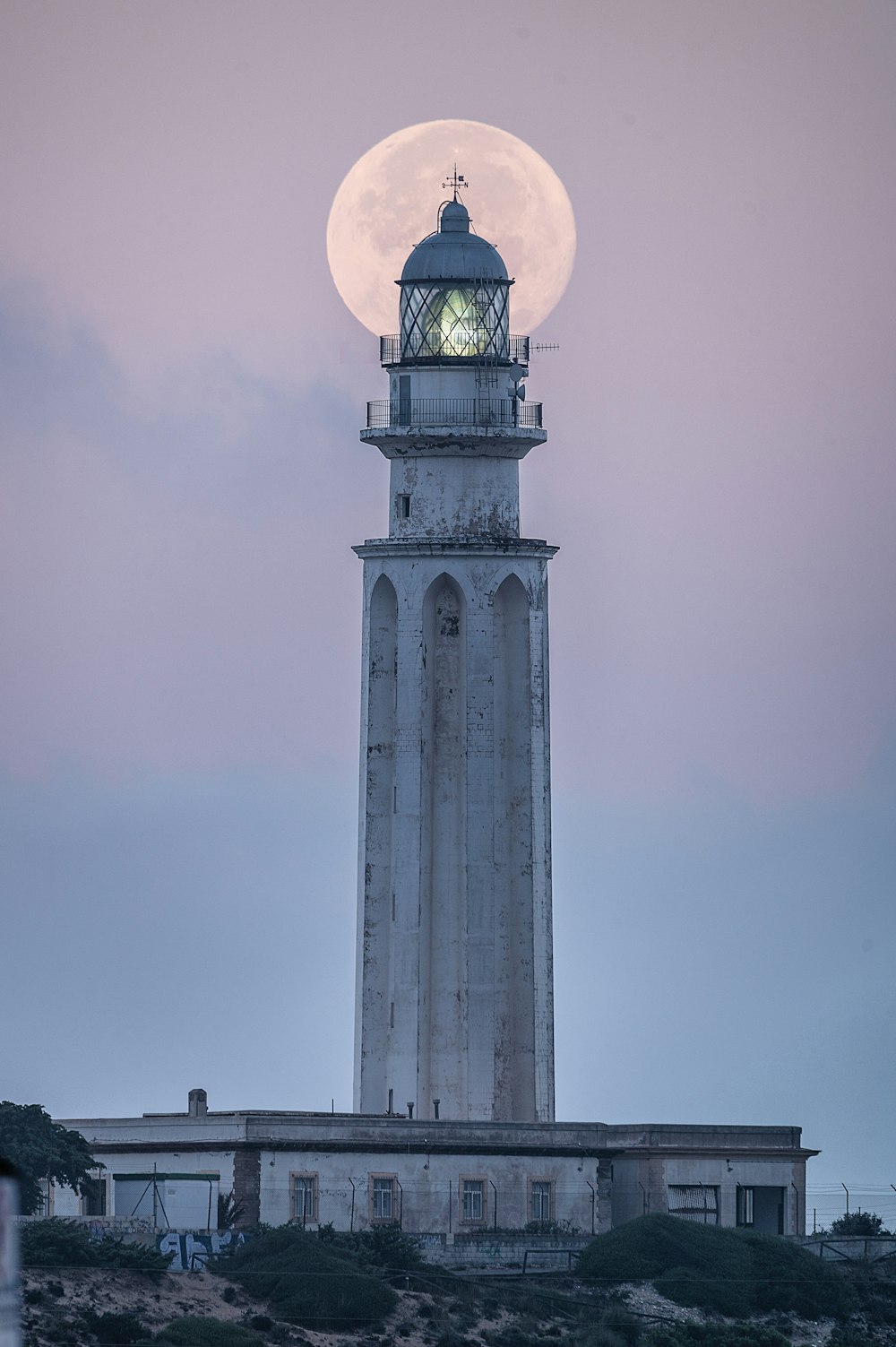 a lighthouse with a full moon in the background