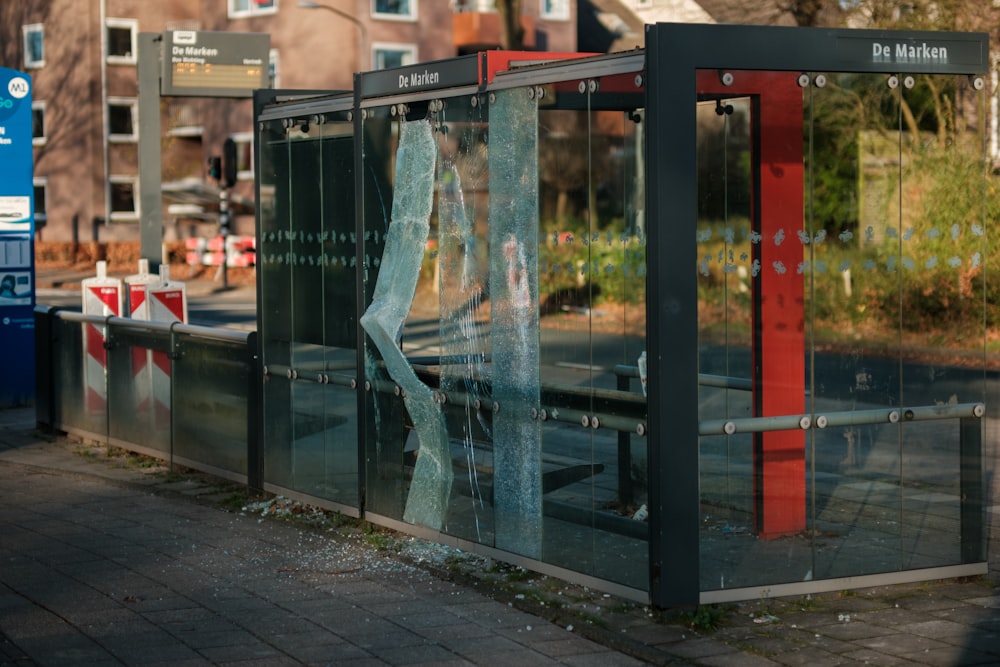 a broken glass bus stop sitting on the side of a road