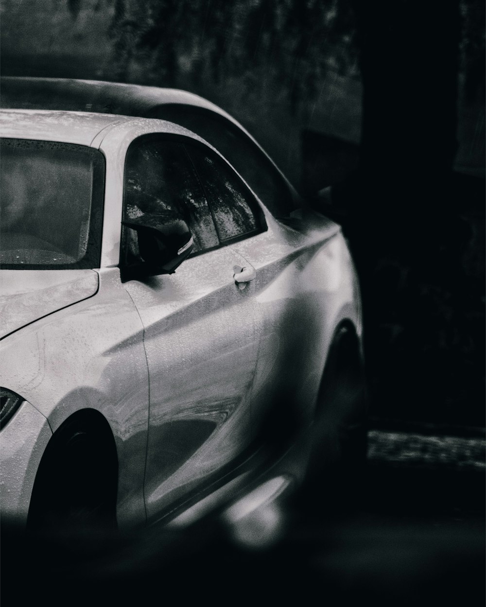 a white car driving down a street next to a tall building