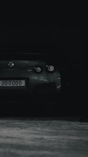 A sleek car parked outside with freshly updated license plates under moody lighting.