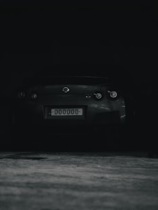 Dark moody image of a license card being held over a car dashboard.