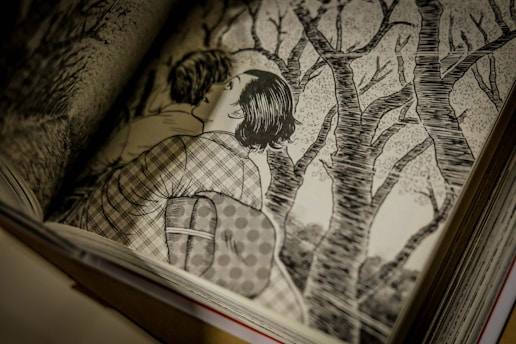 A monochrome illustration in a book shows two people embracing, surrounded by bare trees. The detailed line work creates a textured background, emphasizing the setting of a forest or wooded area.