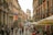 A bustling city street filled with cafes and unique architecture, showcasing vibrant urban life.