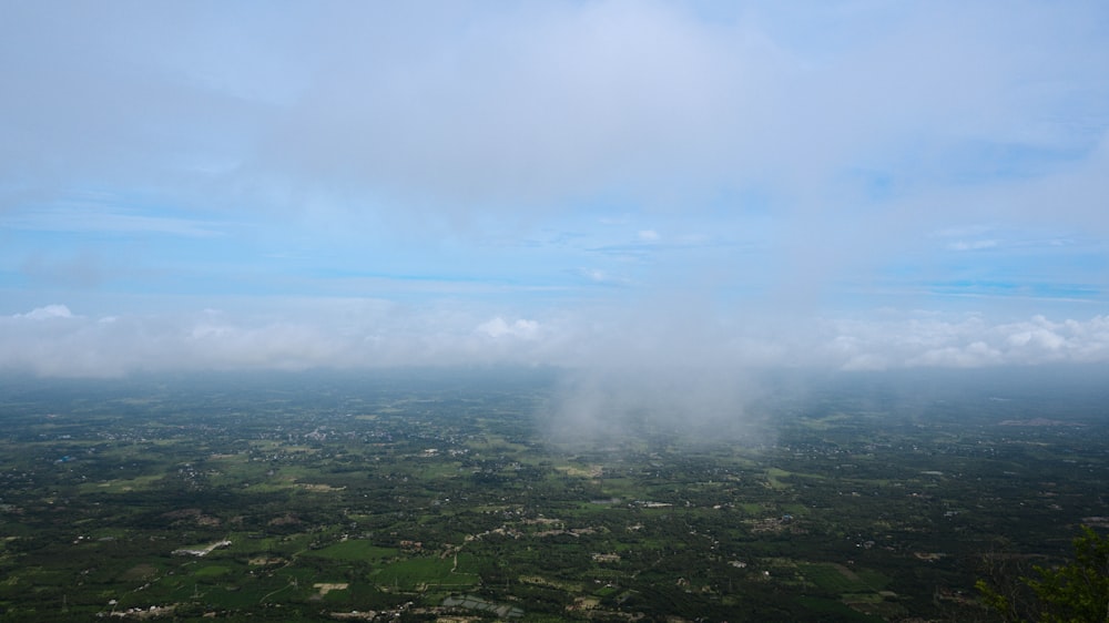 an aerial view of a lush green countryside under a cloudy blue sky