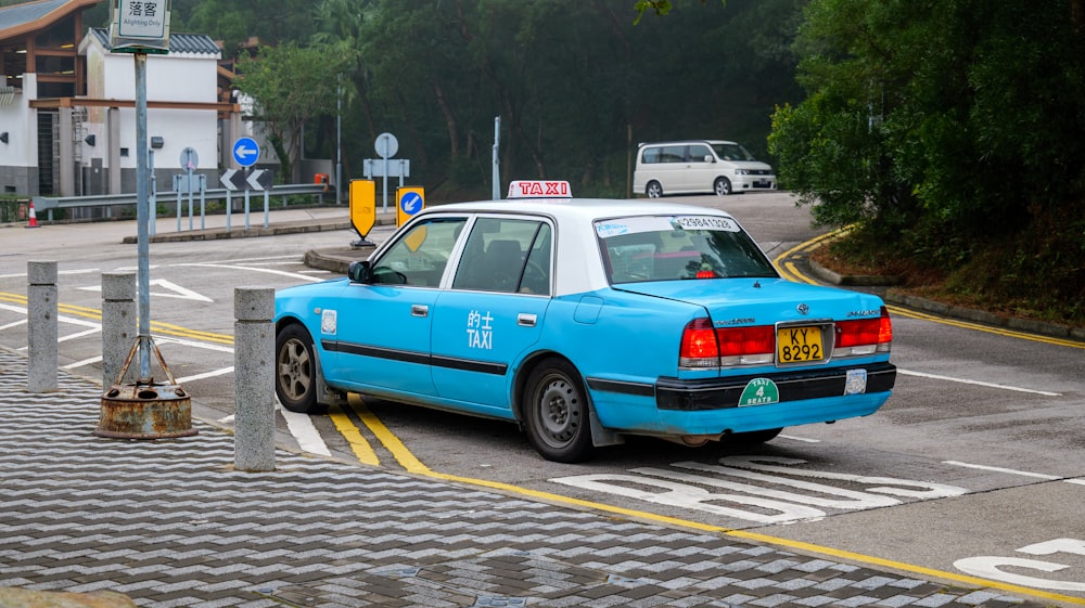 a blue taxi cab driving down a street next to a traffic light
