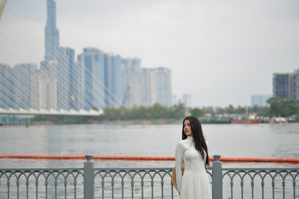 una donna in un vestito bianco è in piedi vicino all'acqua