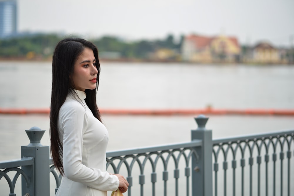 a woman standing on a bridge next to a body of water