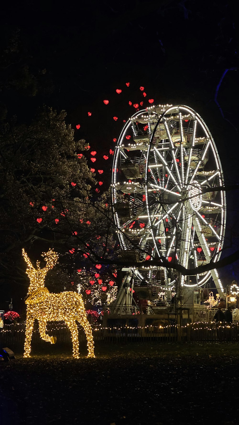 a large ferris wheel with a deer statue in front of it