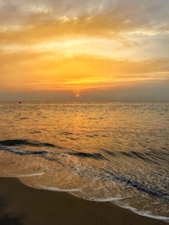 A serene beach at sunset with soft golden light reflecting on gentle waves.