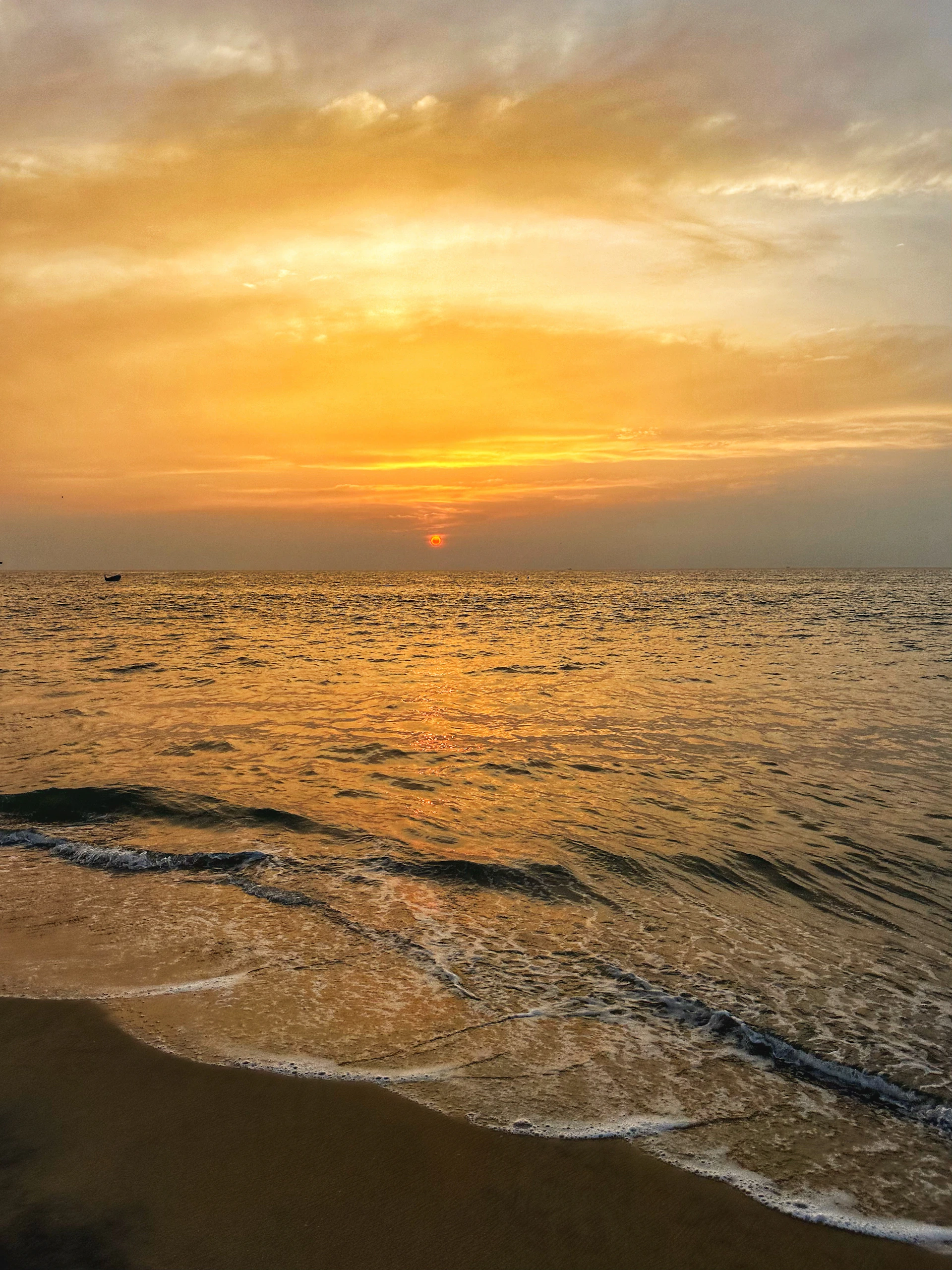 A serene sunset over a quiet beach, capturing warm golden light reflecting on gentle waves.