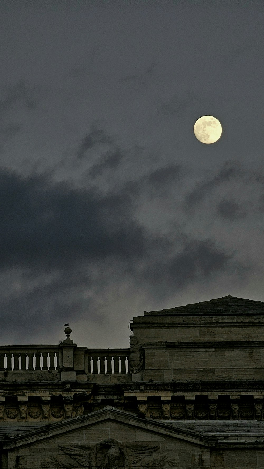 a full moon is seen in the sky above a building