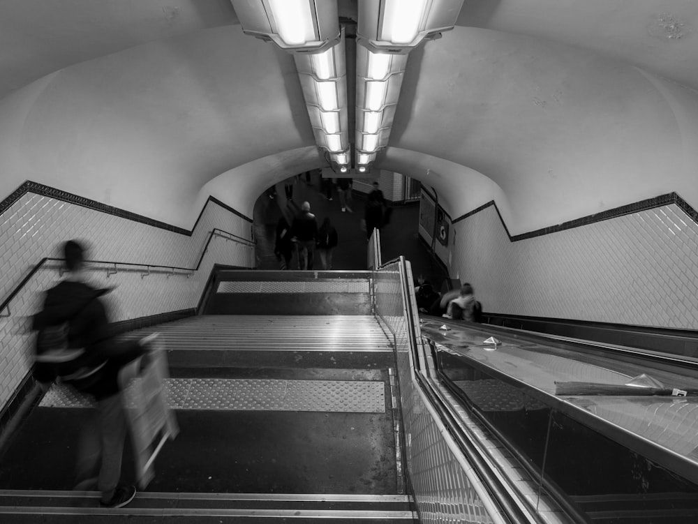 a black and white photo of a person riding an escalator