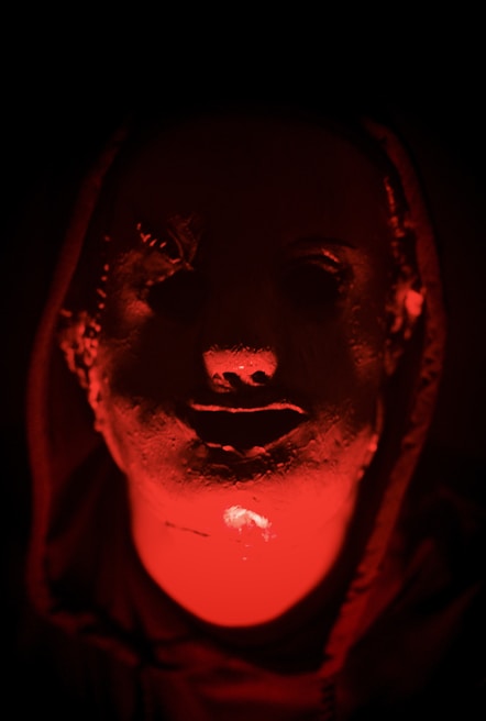 Close-up of a mysterious character in shadow with a glowing red background