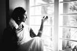 A serene moment of a girl wearing a classic South Indian half-saree, standing by a window with natural light.