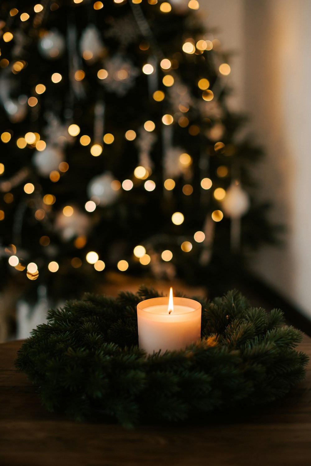 Une bougie allumée sur une table devant un sapin de Noël