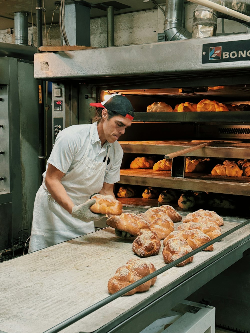 a man in a white shirt is putting some bread in the oven