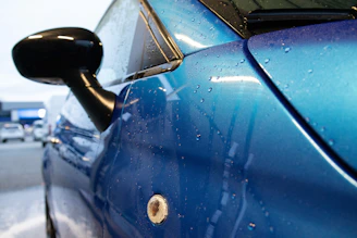 A sleek container of car wash liquid with water droplets glistening on a shiny car surface.