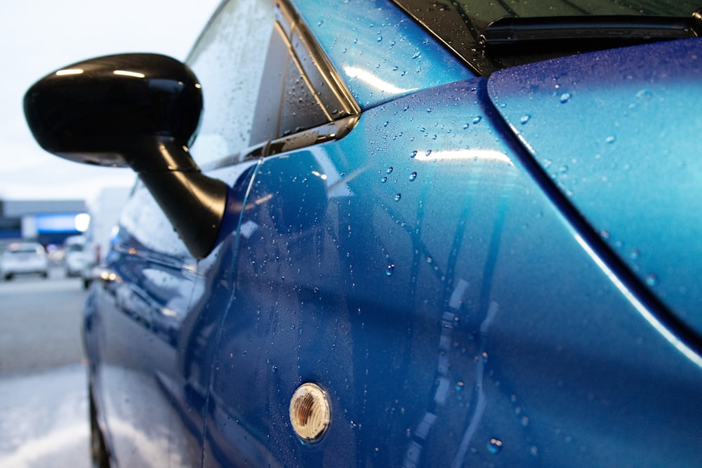 a close up of a blue car with rain drops on it