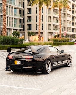 A sleek modern car available for rent in Marrakech, parked by a palm-lined street.