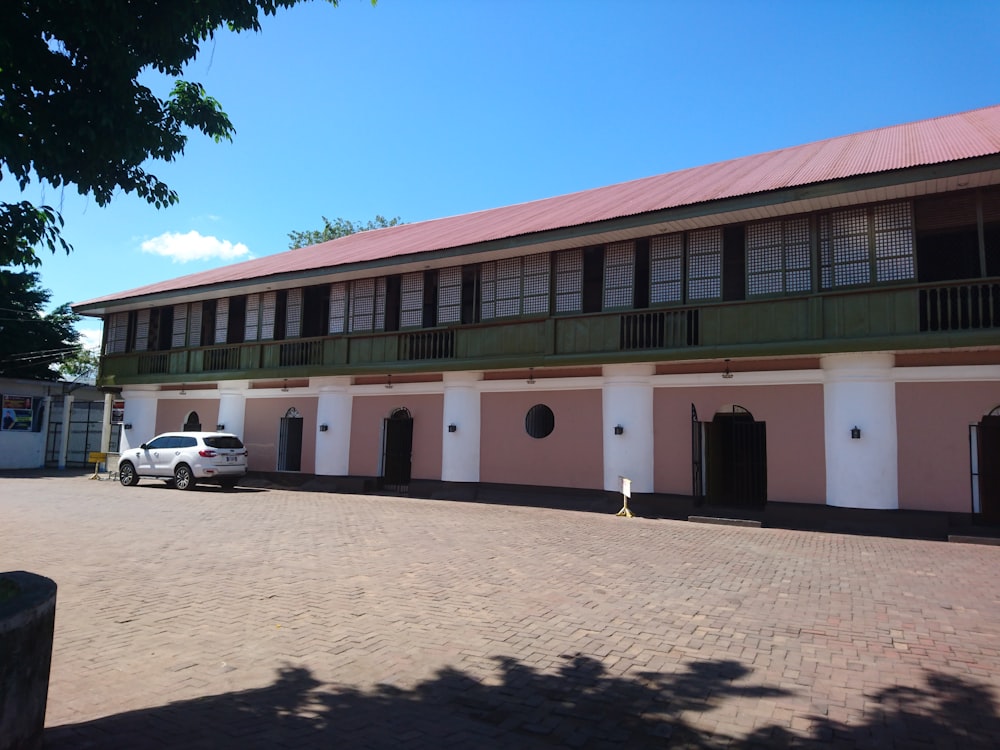 a car parked in front of a pink and white building