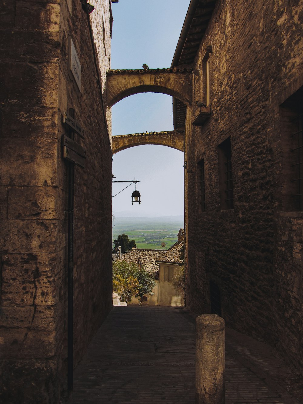 a narrow alley way with an arch leading to the sky
